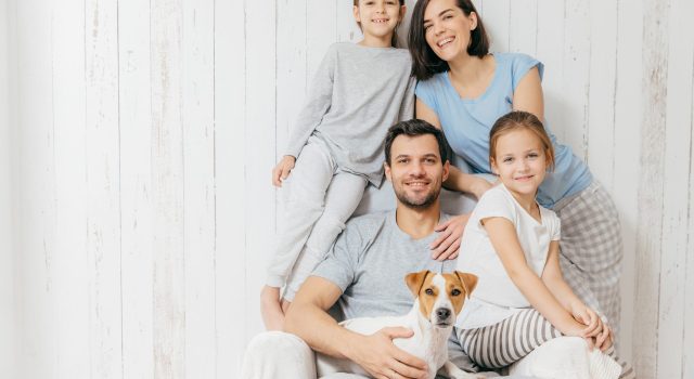Portrait of happy family indoor. Handsome father holds dog, beautiful brunette mother and two daughters, have fun together, pose for family album, spend time together. People, relationships concept