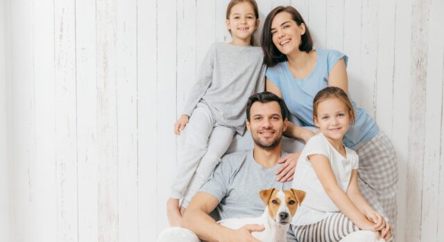 Portrait of happy family indoor. Handsome father holds dog, beautiful brunette mother and two daughters, have fun together, pose for family album, spend time together. People, relationships concept